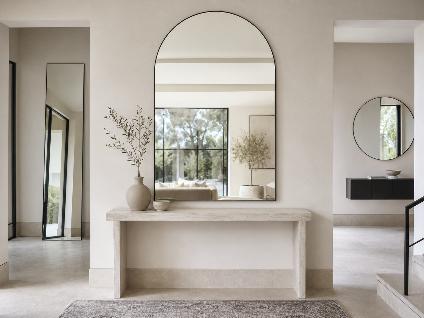 Modern entryway with oversized arched, round and full-length mirrors above a slim stone console