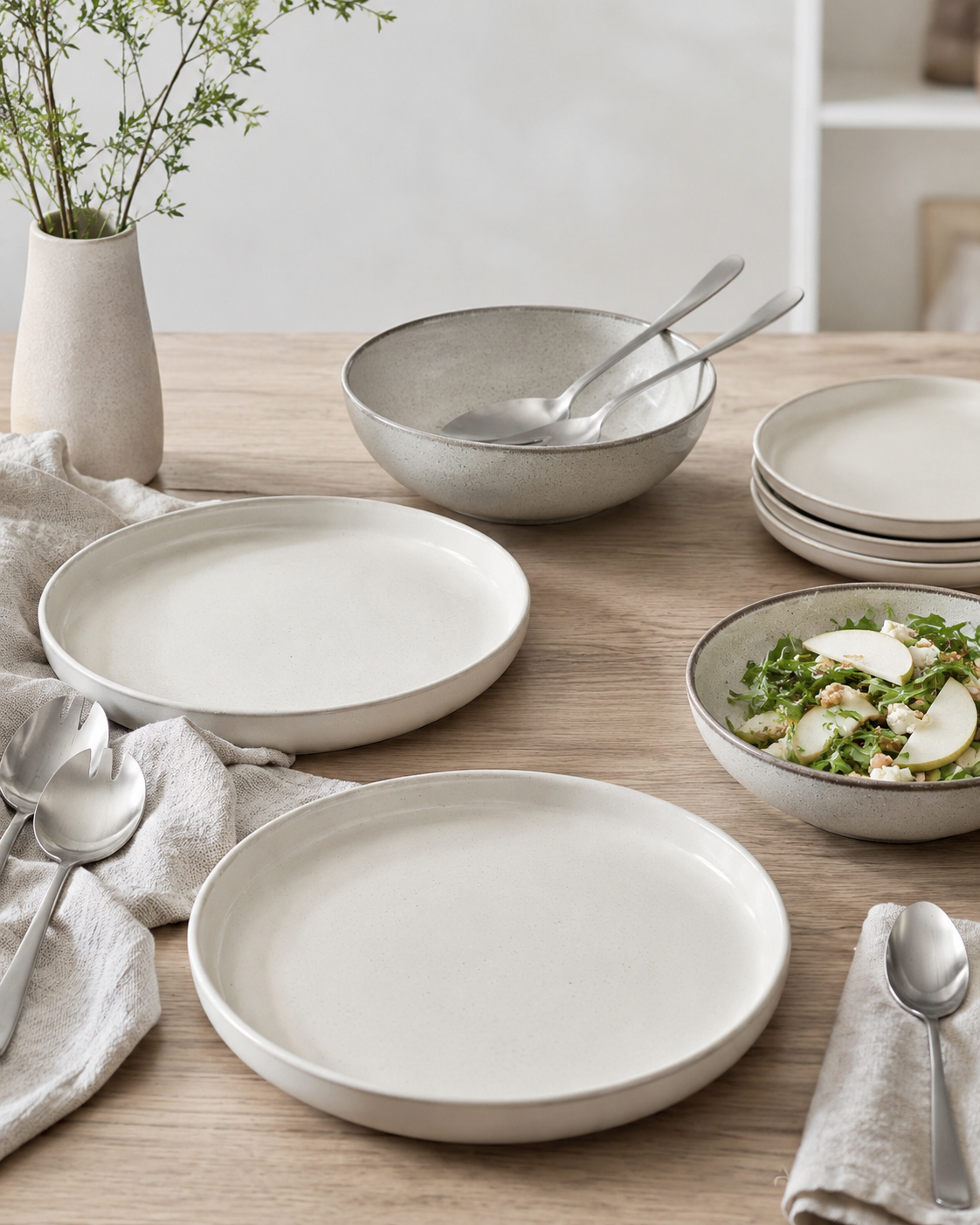Hosting platter scene with ivory serving platters deep bowls speckled stoneware and serving utensils
