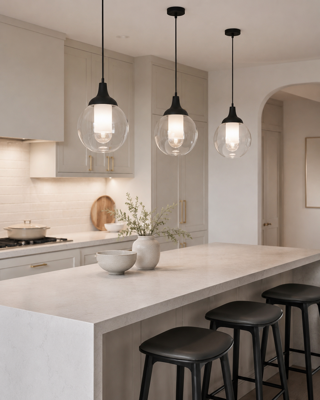 Kitchen island with statement pendant lights above a soft stone counter in a premium neutral kitchen
