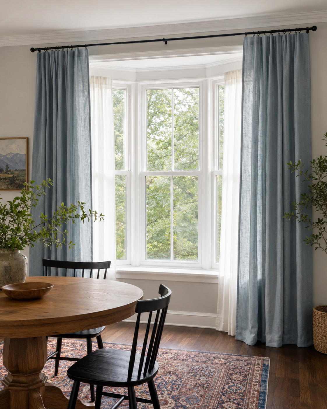 Bay window framed with ceiling-height dusty blue dining room curtains and ivory sheers