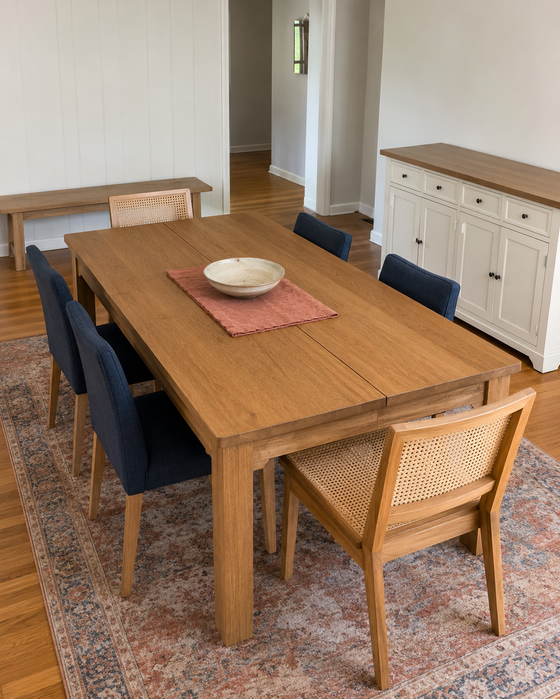 Dining room furniture with an oak table, navy chairs, cane end chairs, olive bench and blue sideboard