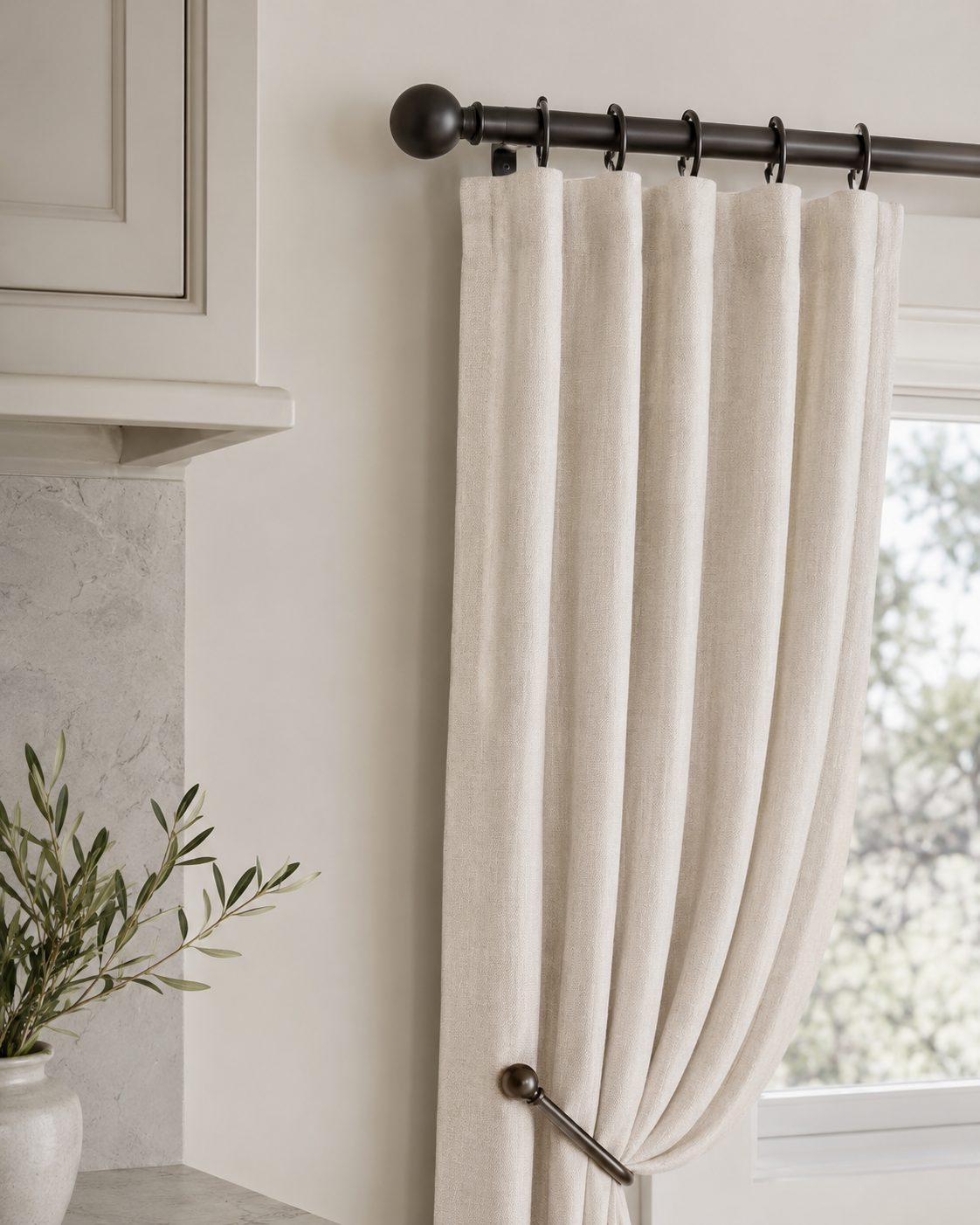 Close-up of polished kitchen curtain hardware with slim curtain rod, clip rings, linen curtain fabric, and minimal tieback detail