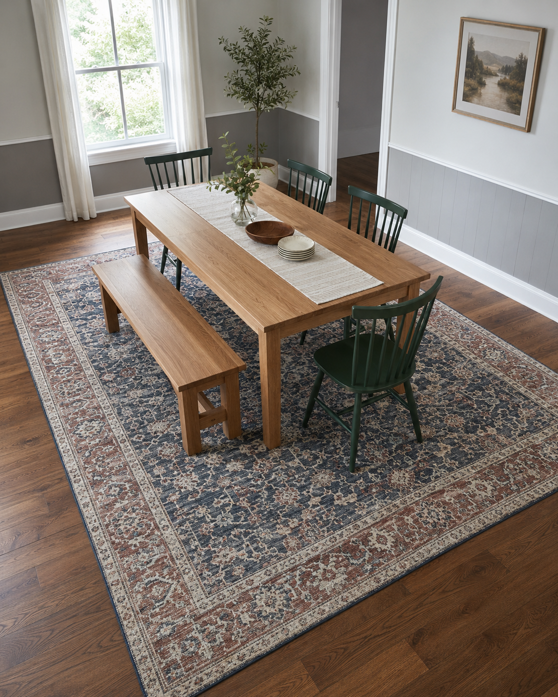 Properly sized patterned dining rug extending beyond an oak table, green chairs and dining bench
