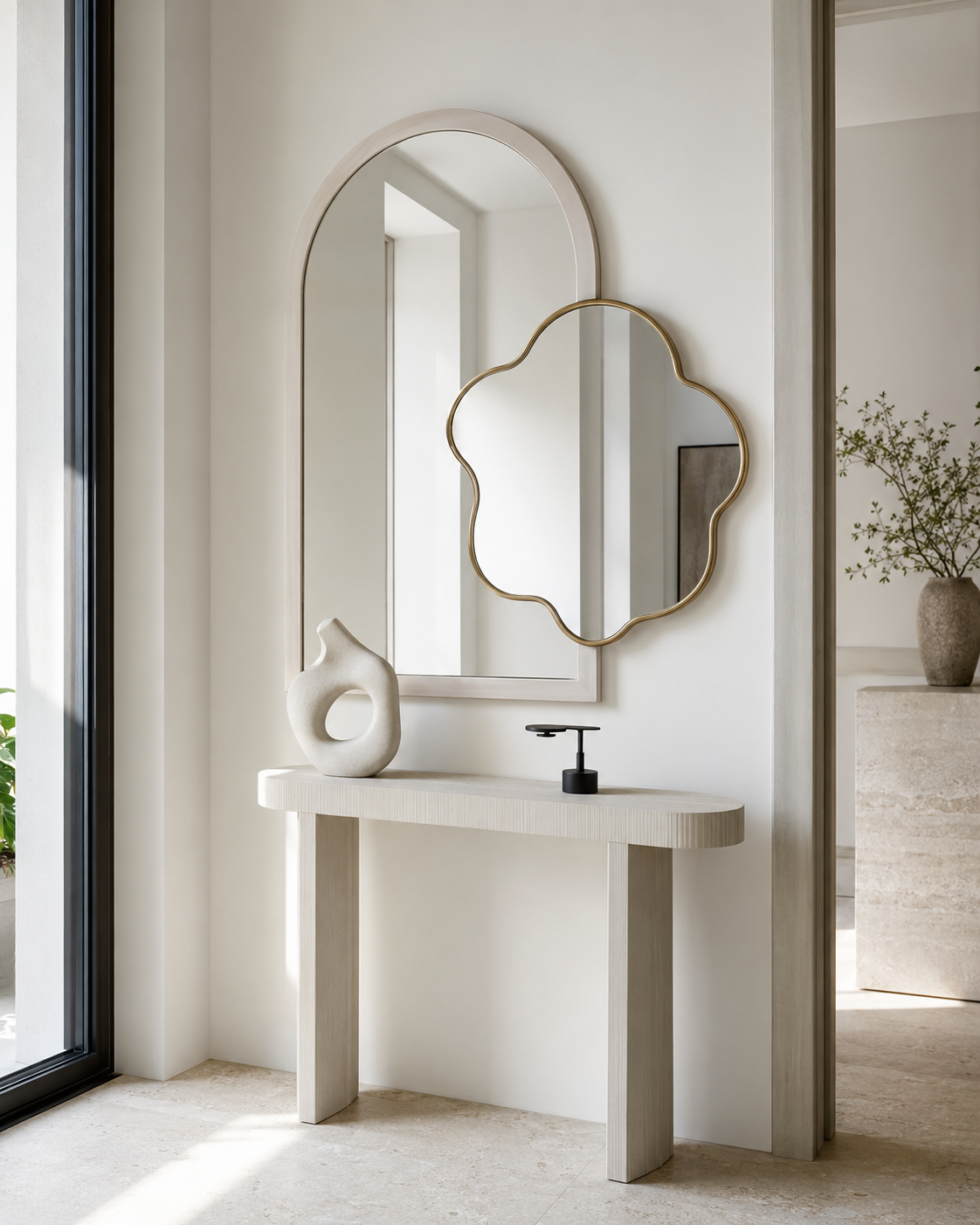White arched mirror and gold cloud-shaped mirror above an ivory console