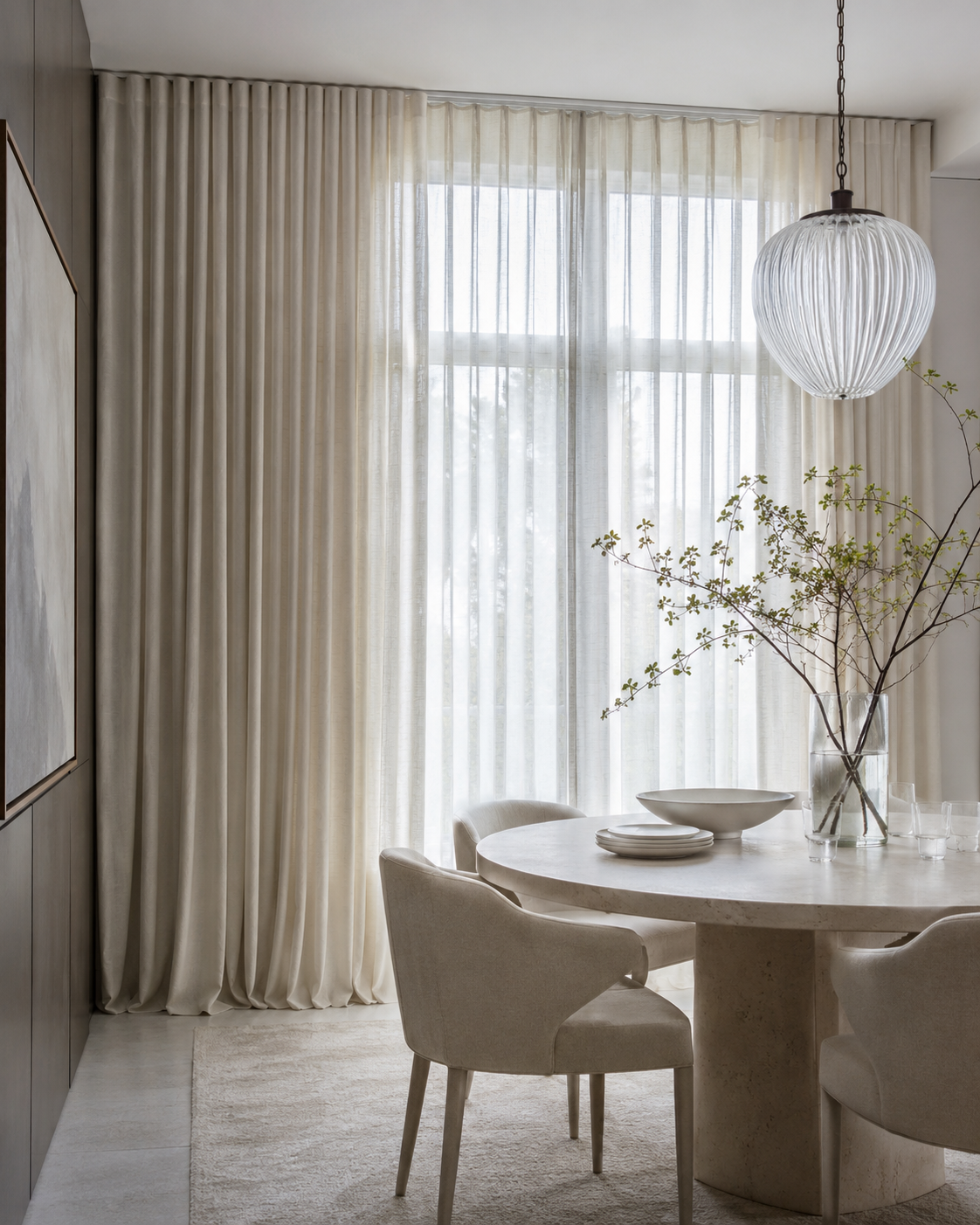 Ivory semi-sheer dining room curtains filtering daylight around a round stone table