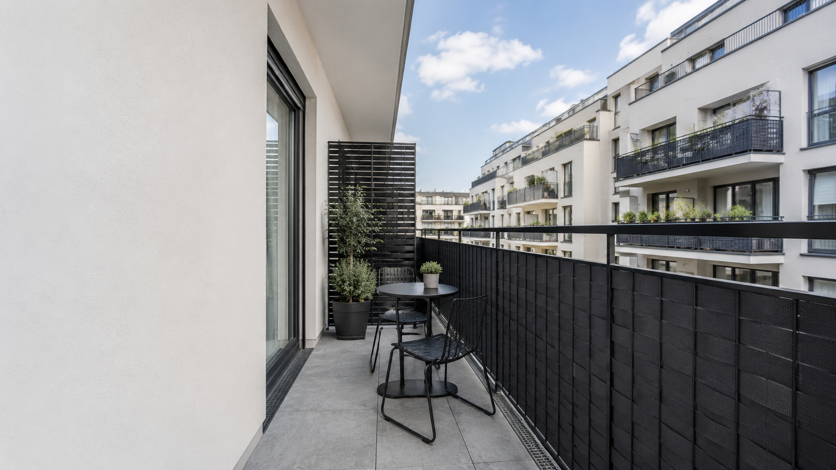 Urban apartment balcony with an exposed neighboring sightline, charcoal railing privacy layer and clear walking path.