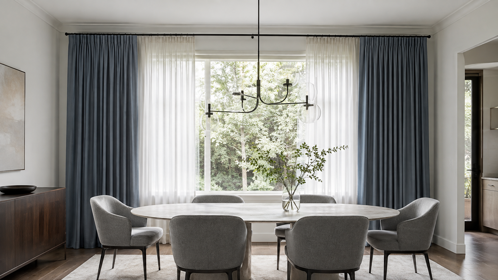 Modern dining room with slate-blue tailored curtains layered over soft white sheers