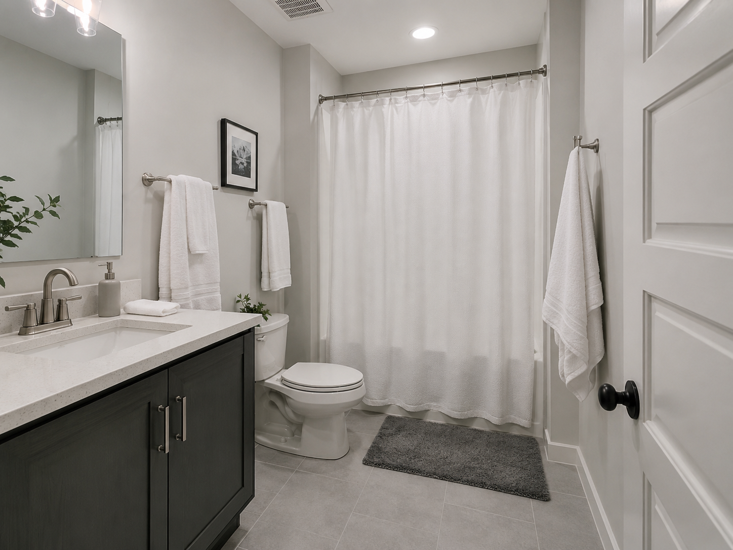 Contemporary bathroom with coordinated towels, floor textile and shower curtain arranged for practical drying.