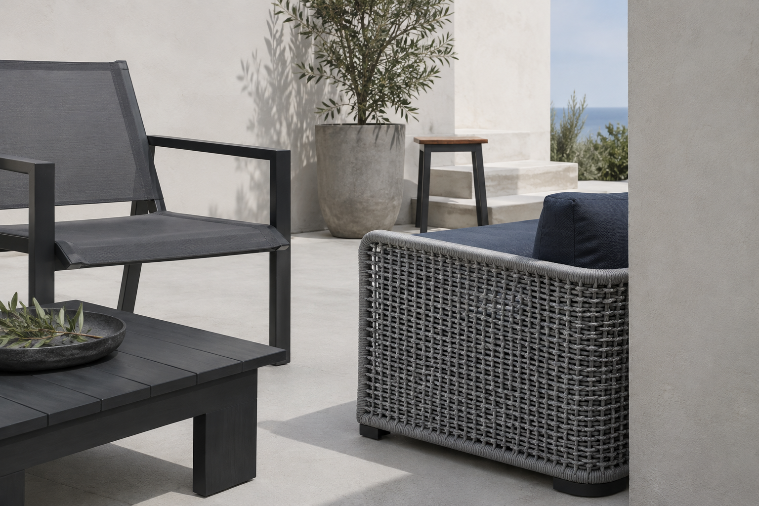 Patio Furniture - Ravnora Decor Contemporary outdoor furniture material study with dark metal, solid polymer-style surfaces, woven texture and cool-gray sling fabric.