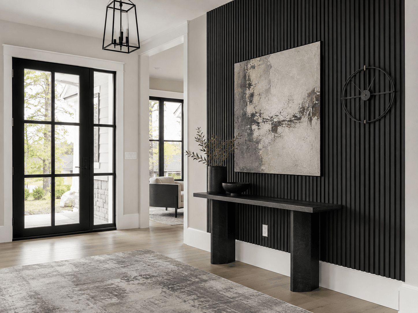 Open contemporary foyer with a dark architectural wall treatment and correctly scaled oversized artwork