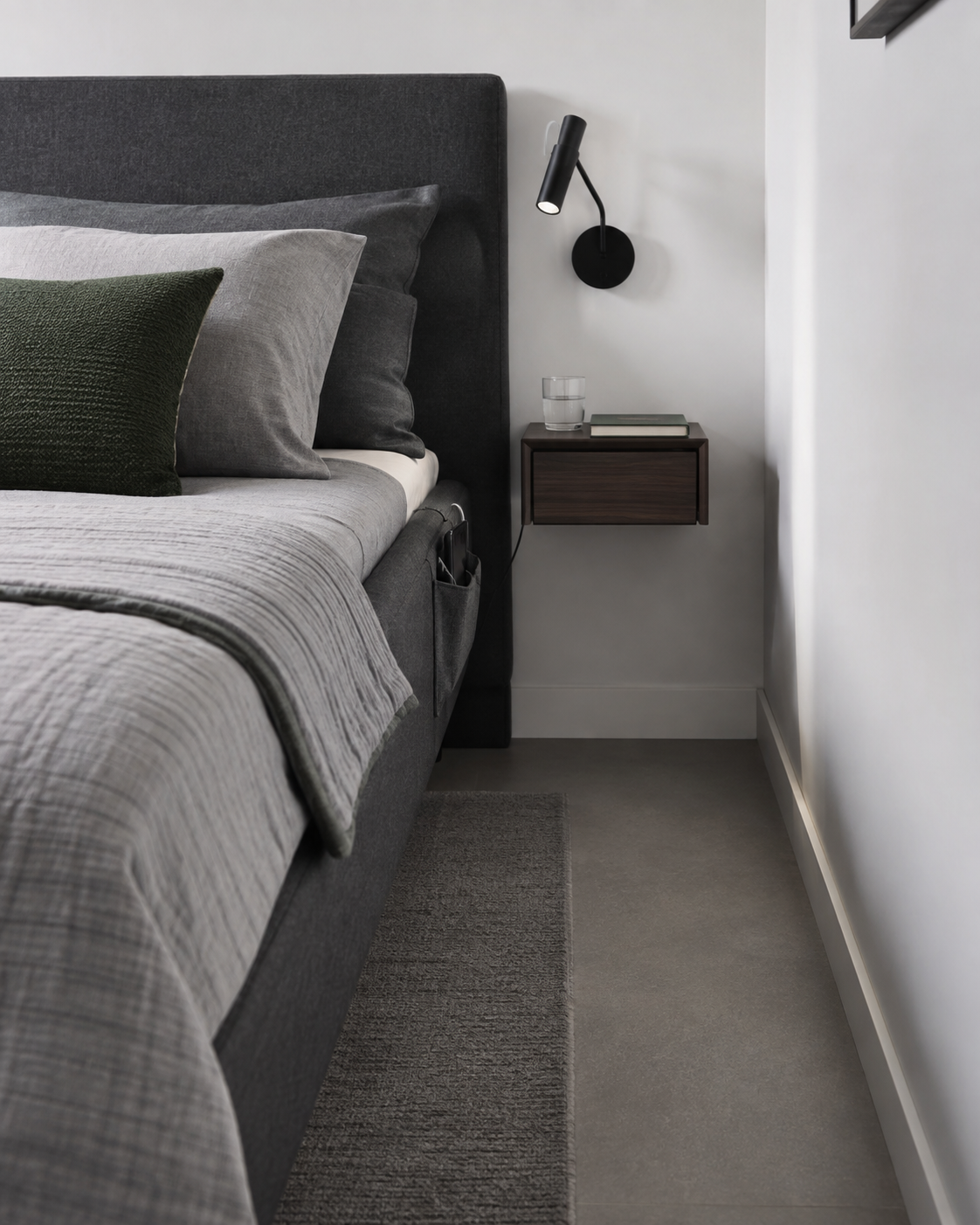 Compact bedside area using a floating surface and wall-mounted light.