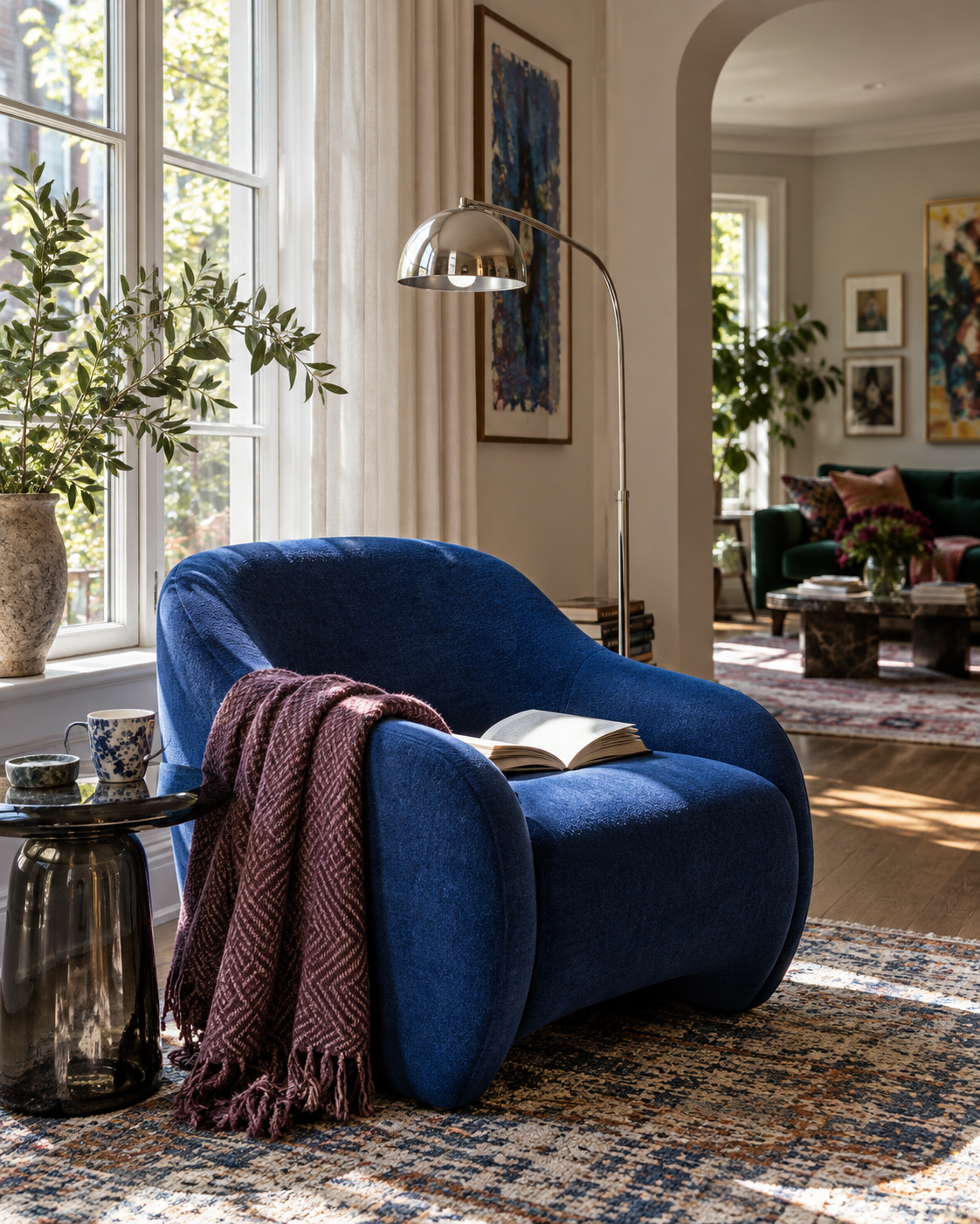 Cobalt blue reading chair by a bright window with floor lamp, side table and book
