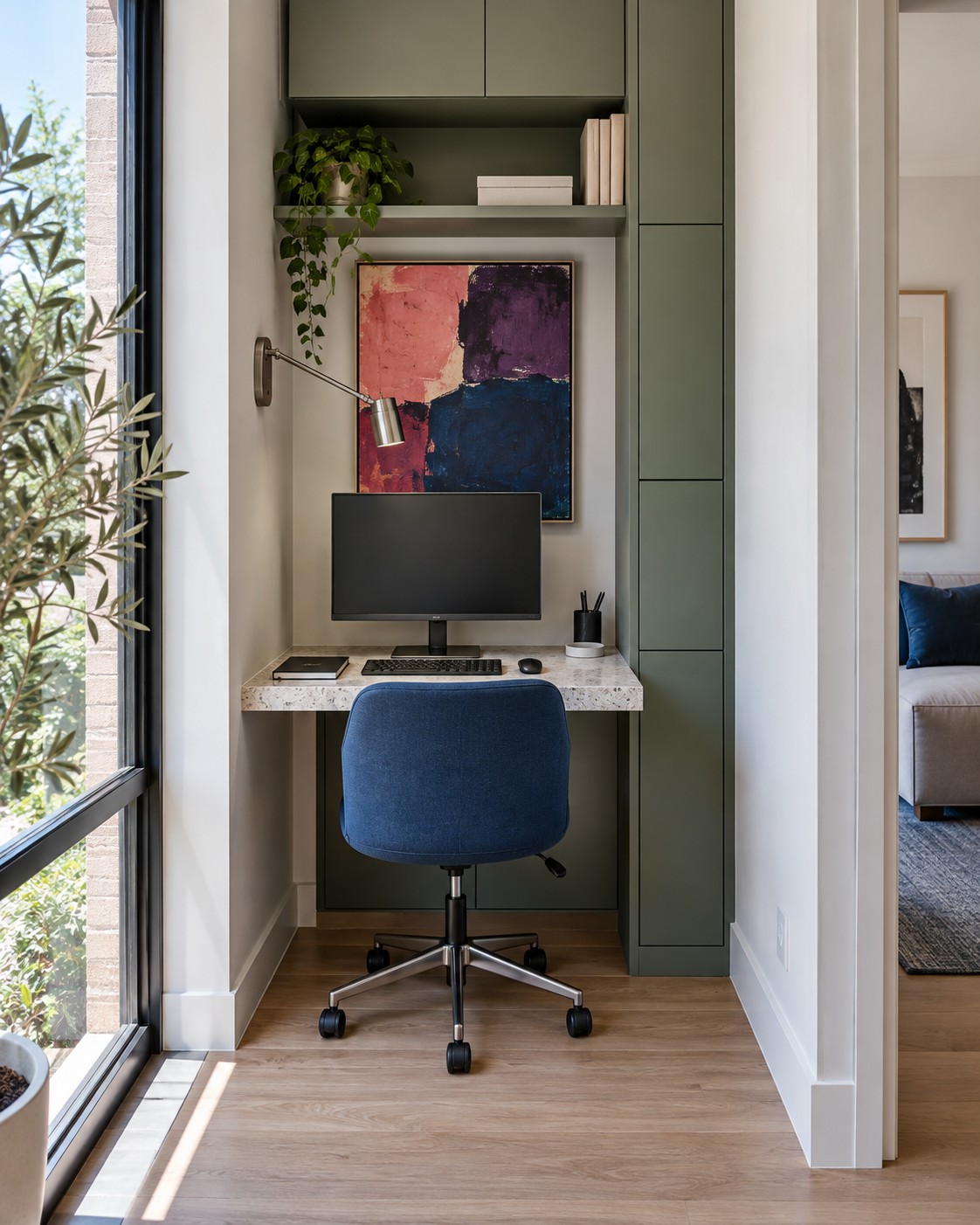 Compact home-office alcove using a shallow desk, blue chair, wall lighting and vertical storage.
