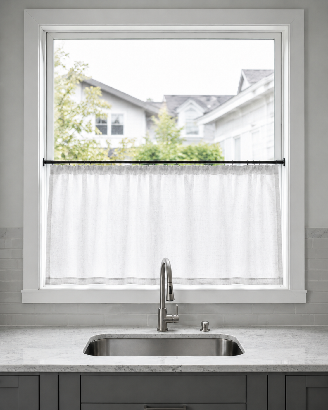 Kitchen Curtains & Window Styling - Ravnora Decor White café curtain covering the lower half of a kitchen sink window while the upper glass remains open.