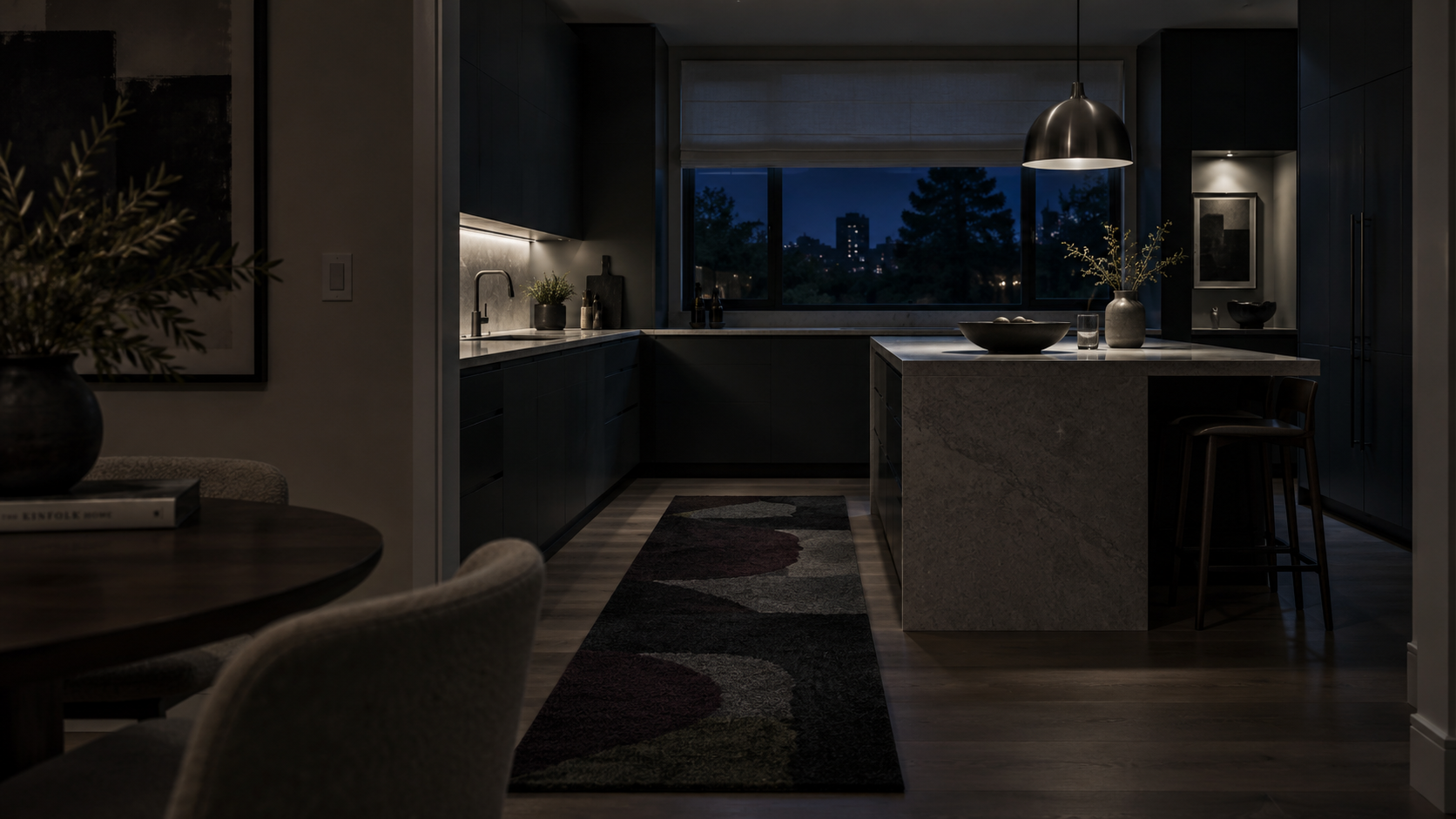 Contemporary kitchen after dark with layered low lighting, a patterned runner and softly treated window.